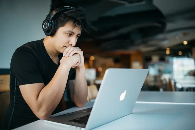 Uczeń w słuchawkach pracujący przy laptopie