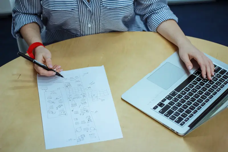 Rozwiązywanie zadań na papierze obok laptopa